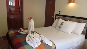 Ein Hotelzimmer mit einem Bett, einer farbenfrohen Decke, weißen Kissen und einer wandmontierten Leuchte.