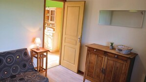 A room with a patterned sofa, a small table with a lamp, a wooden cabinet, and a door leading to another room. - 1 bedroom stunning home in Hames-Boucres (Hames-Boucres)