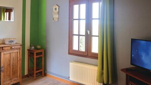A room with a wooden cabinet, a small table with a lamp, a window with curtains, a radiator, and a television on a stand. - 1 bedroom stunning home in Hames-Boucres (Hames-Boucres)