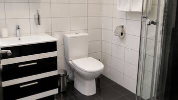 A modern bathroom with a black and white vanity, a toilet, and a glass shower enclosure.