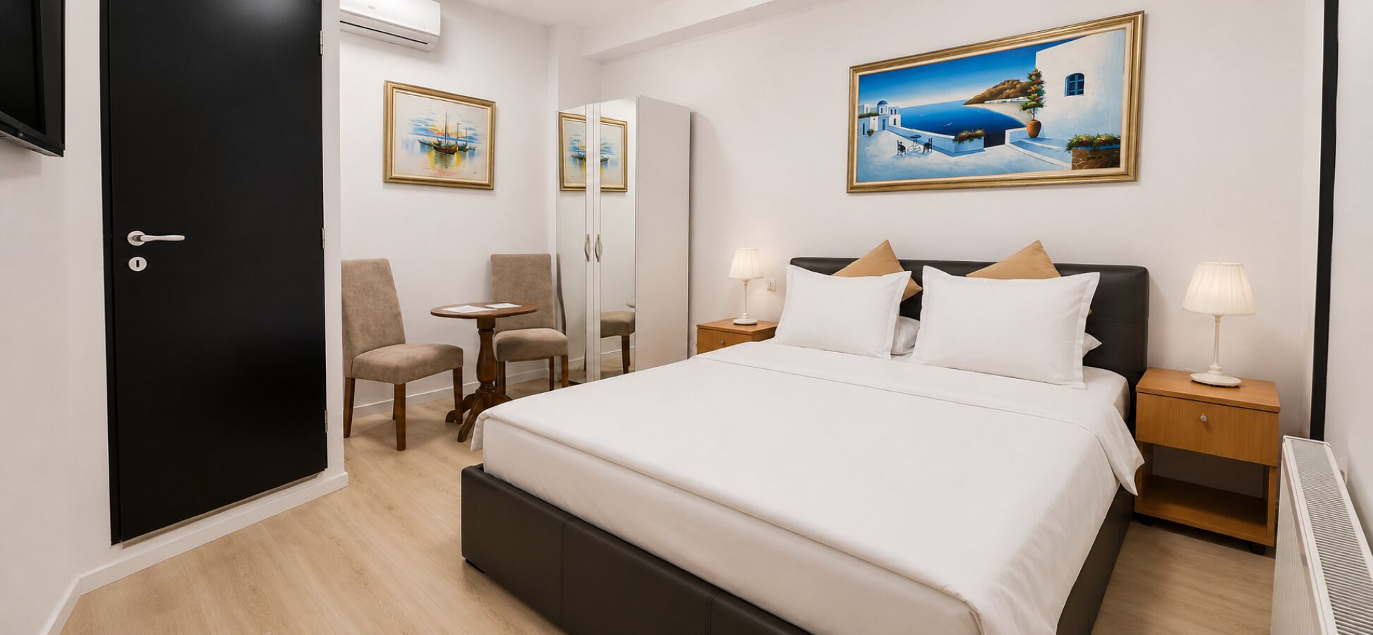 Une chambre d’hôtel avec un lit, deux tables de chevet, une chaise, un bureau et une porte.