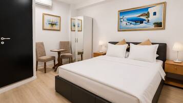 A hotel room with a bed, two bedside tables, a chair, a desk, and a door.