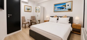Una habitación de hotel con una cama, dos mesitas de noche, una silla, un escritorio y una puerta.
