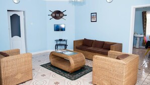 Una sala de estar con muebles de mimbre, un televisor y una lámpara de techo.