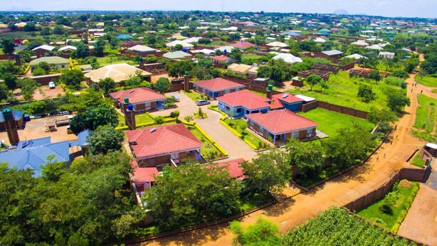Una zona residencial con varias casas, algunas con techos rojos, rodeada de vegetación y un camino de tierra.