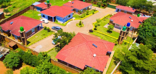 An aerial view of a residential area with multiple houses, each with red roofs and solar panels.