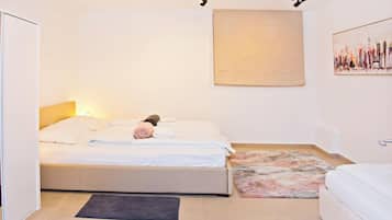 Un dormitorio con una cama, una alfombra pequeña, un cuadro en la pared y una puerta.
