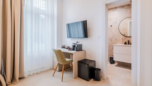 A hotel room with a desk, chair, TV, and a small black refrigerator. - Flowers Premium Apartments & Rooms (Zagreb)
