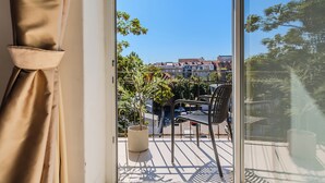A balcony with a potted plant, a chair, and a table. - Flowers Premium Apartments & Rooms (Zagreb)
