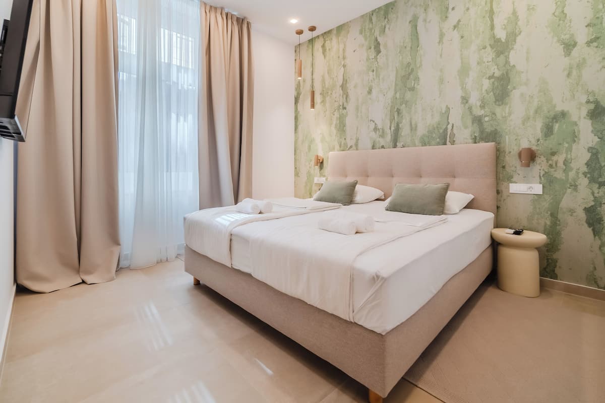 A neatly made bed with pillows, a bedside table, and a wall-mounted light fixture.