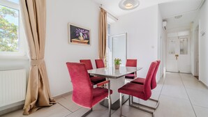 A dining area with a table and chairs, a window with curtains, and a framed picture on the wall. - Flowers Premium Apartments & Rooms (Zagreb)