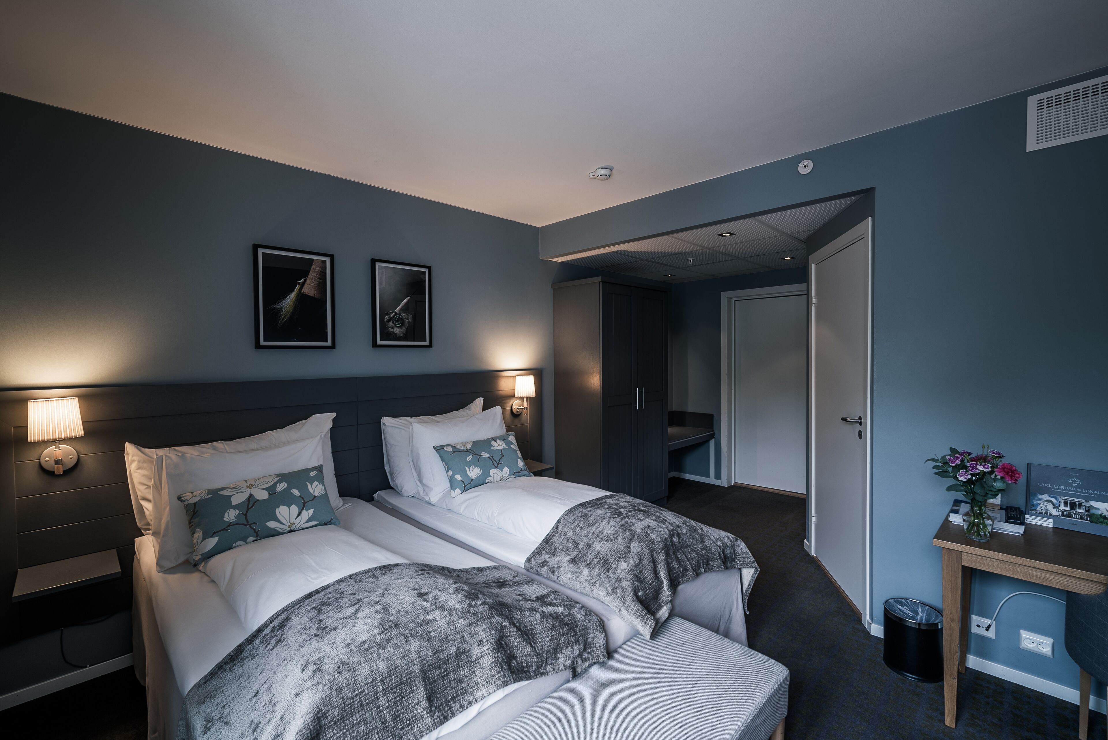 Habitación de hotel con dos camas, un escritorio y una mesita de noche.