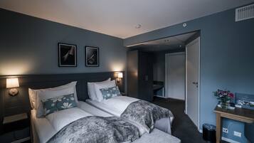 Habitación de hotel con dos camas, un escritorio y una mesita de noche.