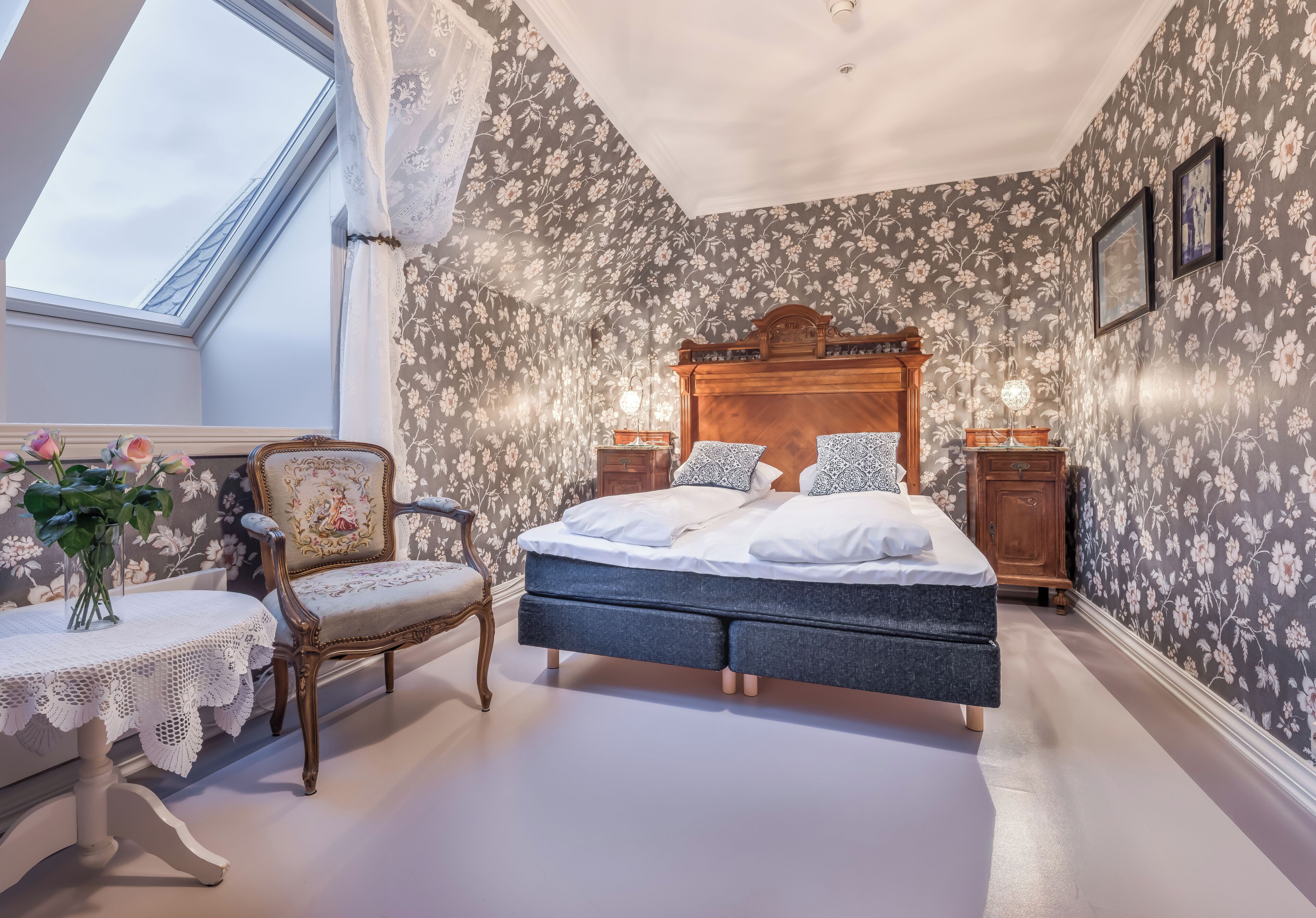 Ein Schlafzimmer mit einem Bett, einem Sessel, einem Tisch und einem Fenster.
