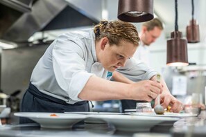 A chef preparing food in a modern kitchen with stainless steel appliances and pendant lighting. - Gloppen Hotell - by Classic Norway Hotels (Gloppen)