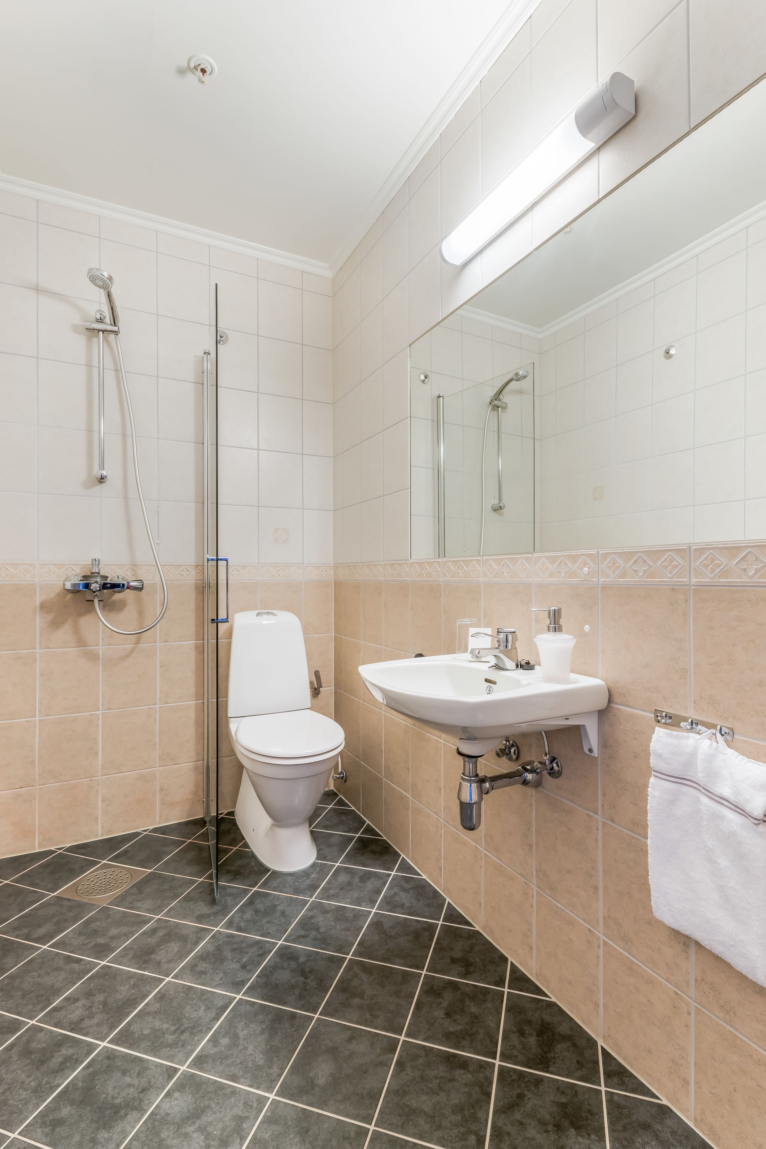 Et badeværelse med toilet, håndvask og bruser.
