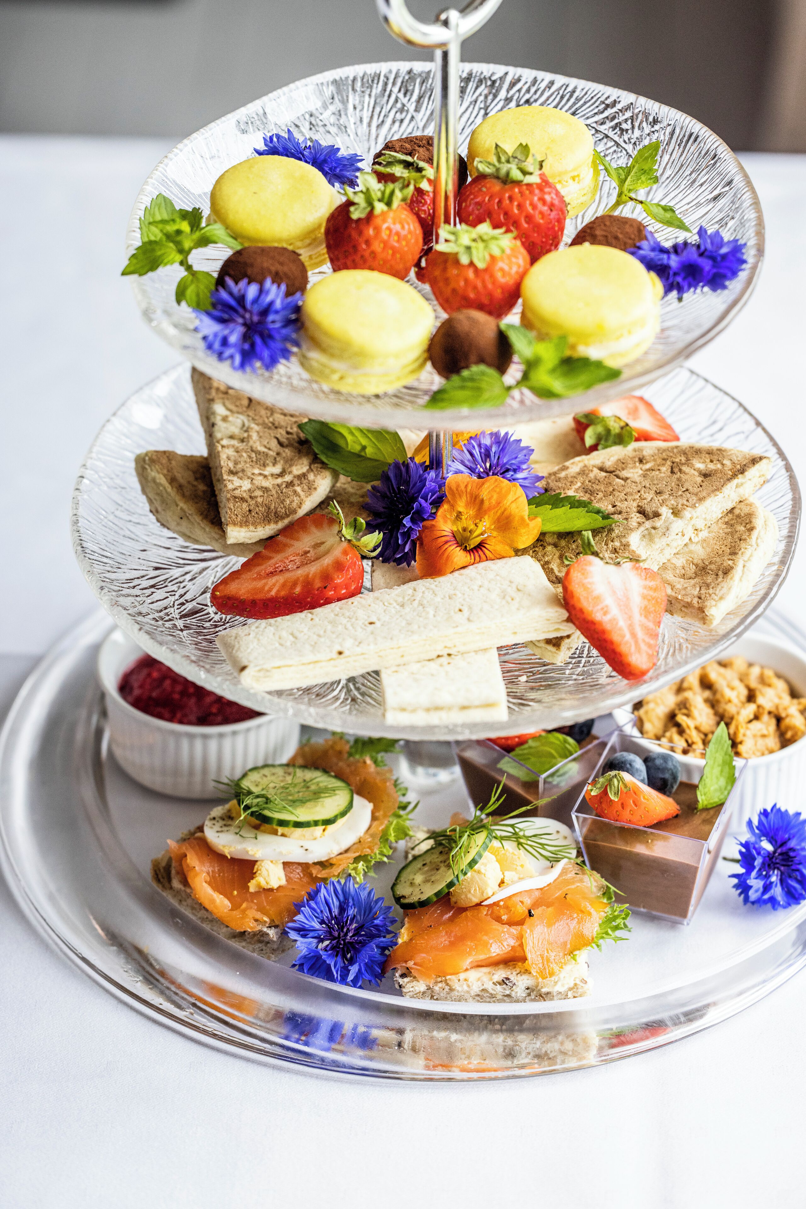 Un plato de postres de varios niveles, con diversas pastelerías y frutas.