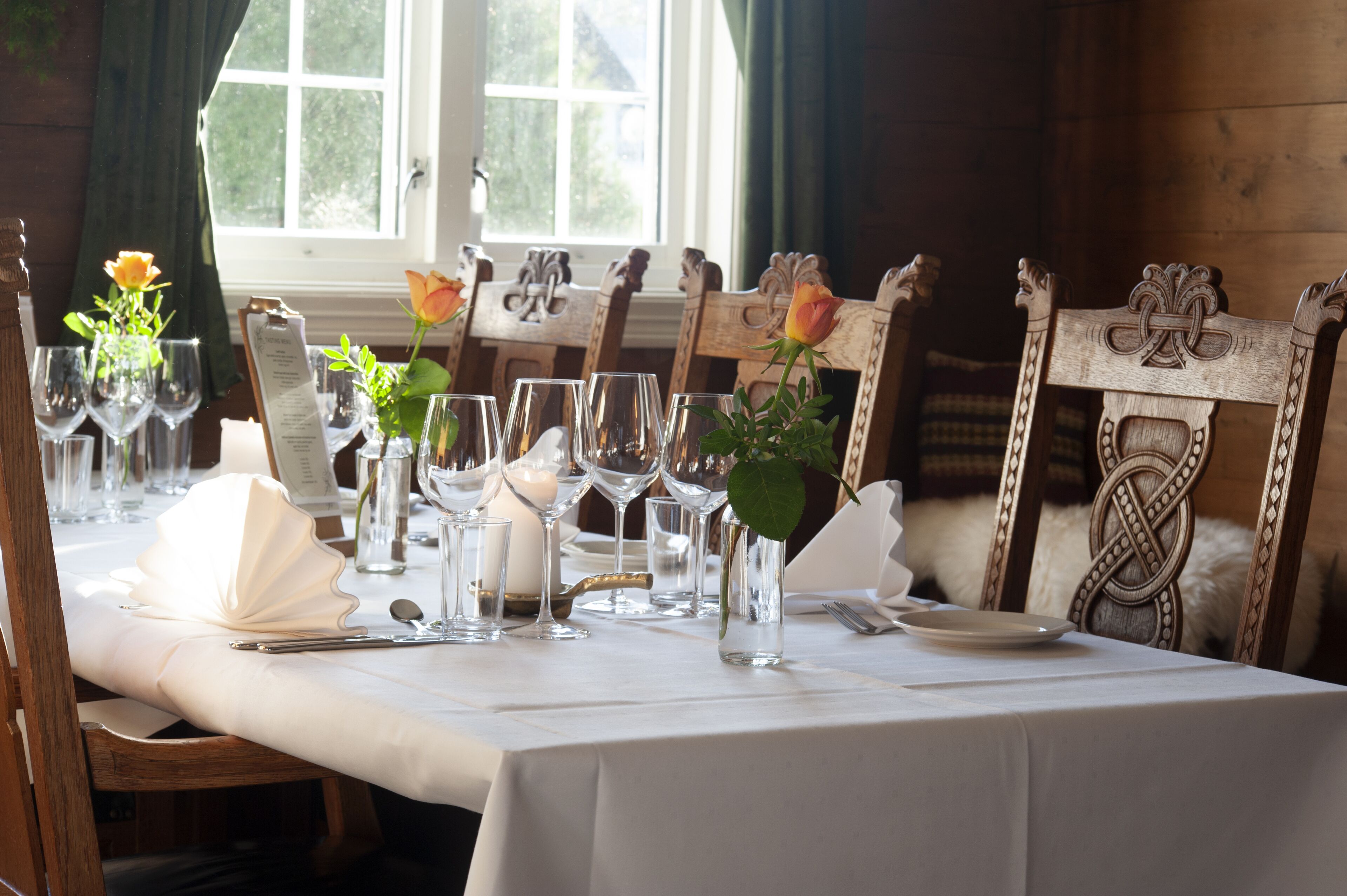 A table set for a meal with glassware, a candle, and a menu.