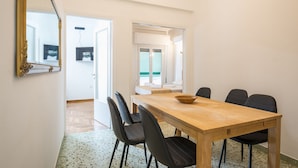 A dining area with a wooden table, black chairs, and a large mirror on the wall. - Victoria Best Apartment (Athens)