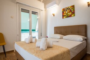 A hotel room with a bed, a chair, a painting, and a balcony. - Victoria Best Apartment (Athens)