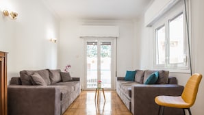 A living room with two grey sofas, a small wooden table with a vase, and a yellow chair. - Victoria Best Apartment (Athens)