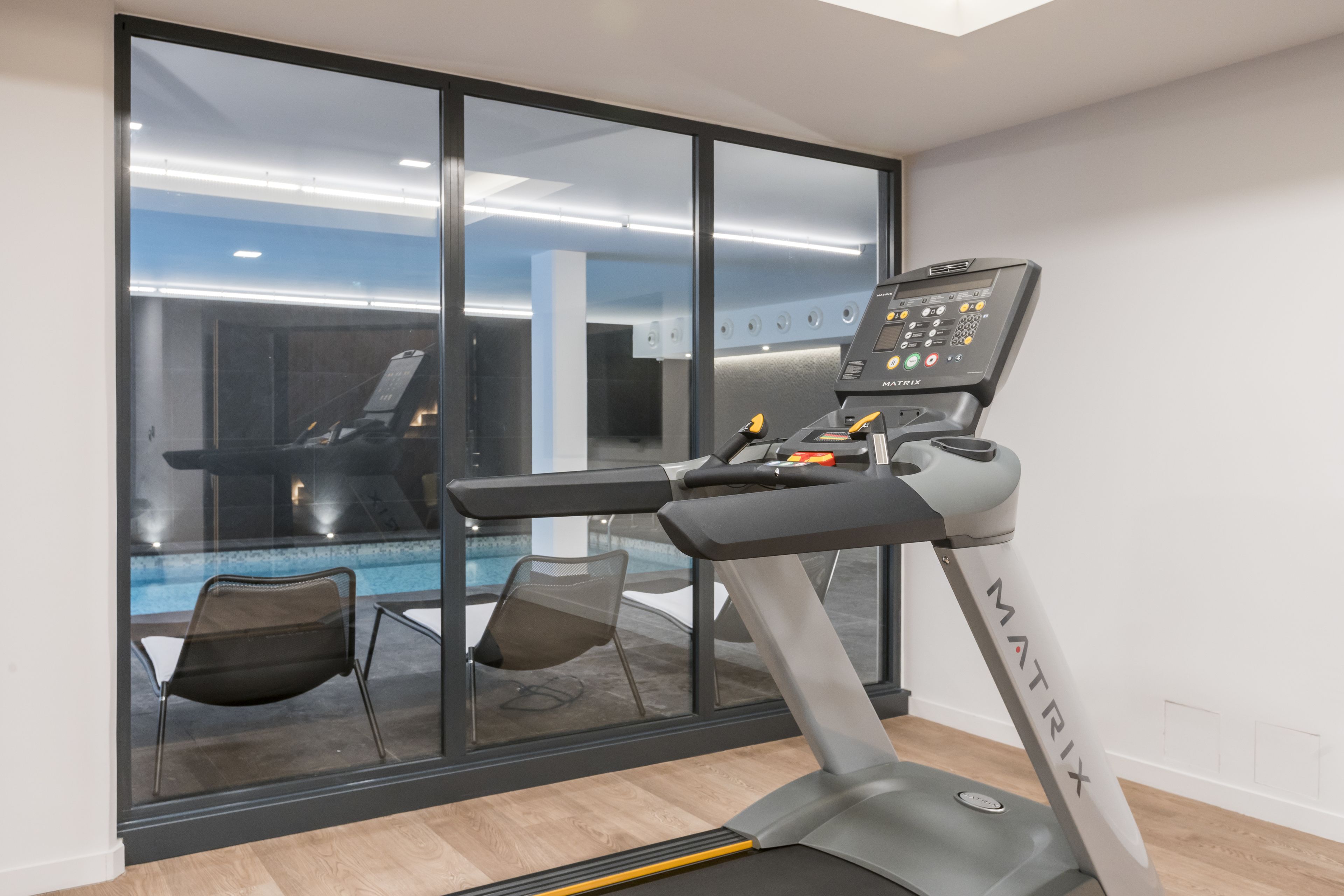 Una cinta de correr en una habitación con un ventanal que da a una zona de piscina.
