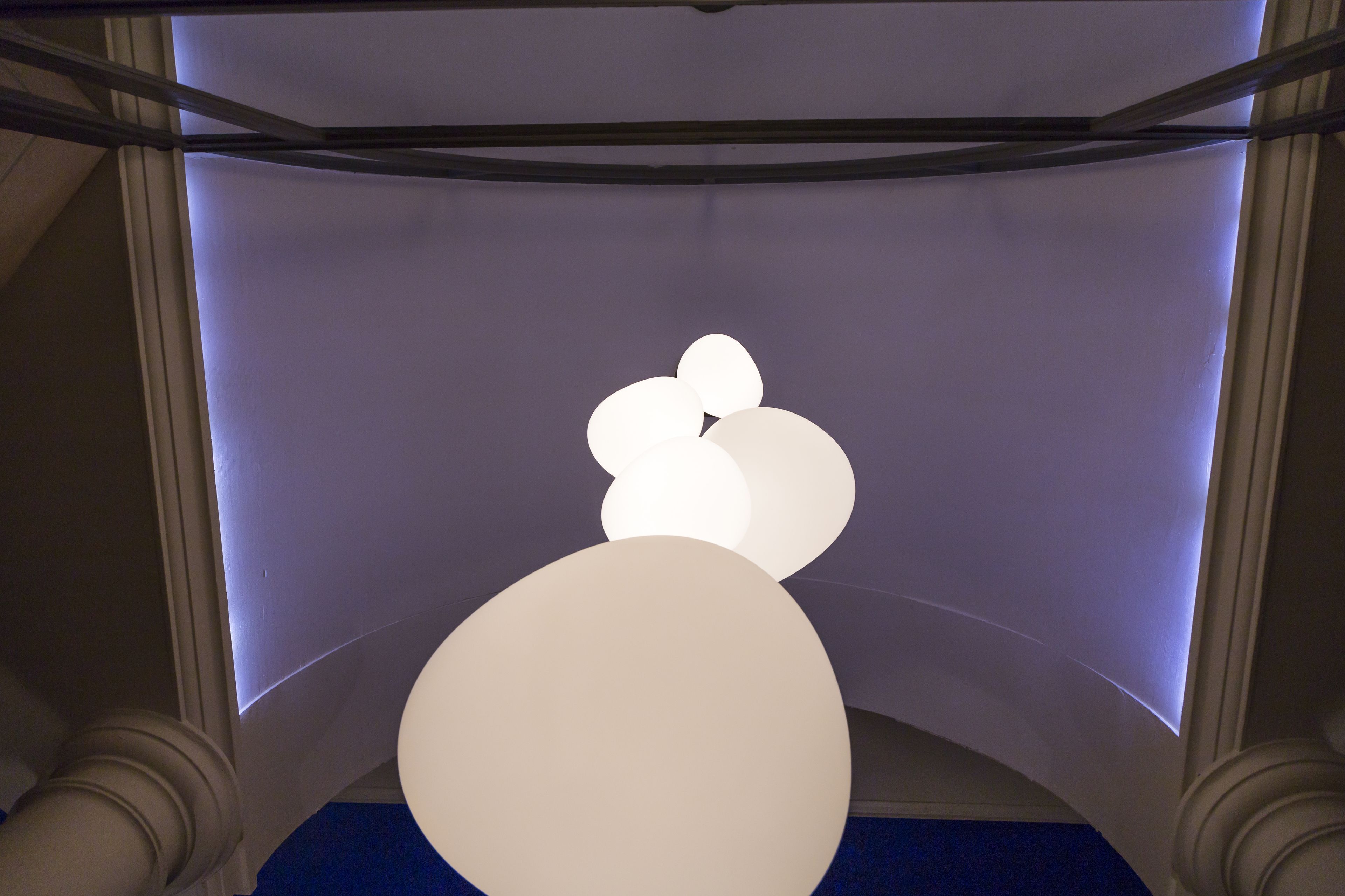 A ceiling with a geometric light fixture and a large, illuminated wall.