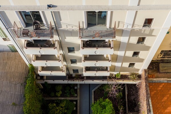 A multi-story building with balconies, a central courtyard, and greenery. - Nemea Appart Hotel Cannes Palais (Cannes)