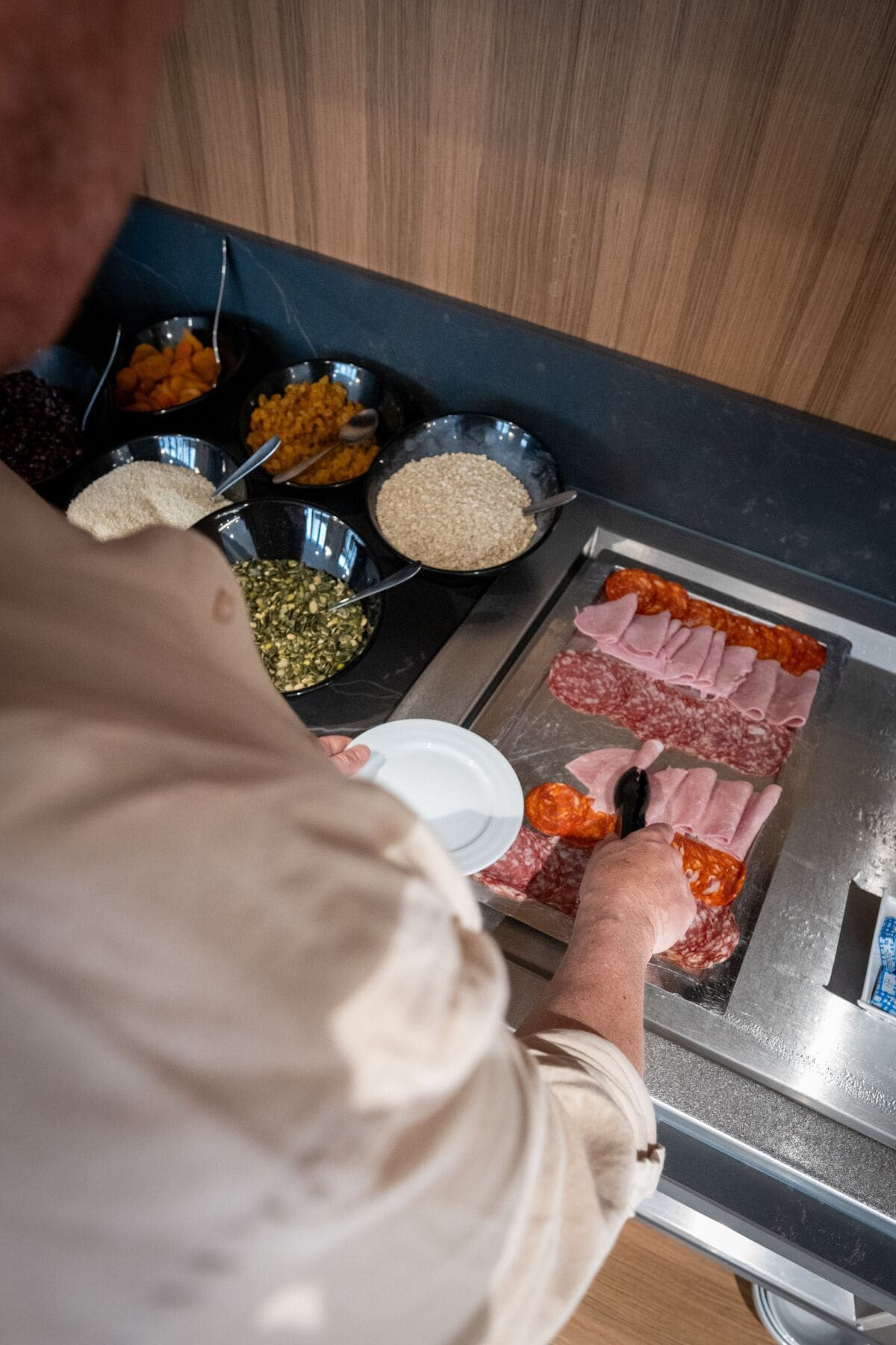 Una persona preparando una comida con diversos ingredientes y carnes en una parrilla.