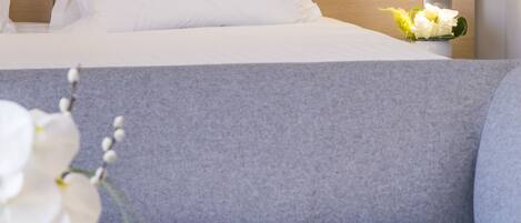 A modern hotel room with a bed, a sofa, and a nightstand with a lamp.