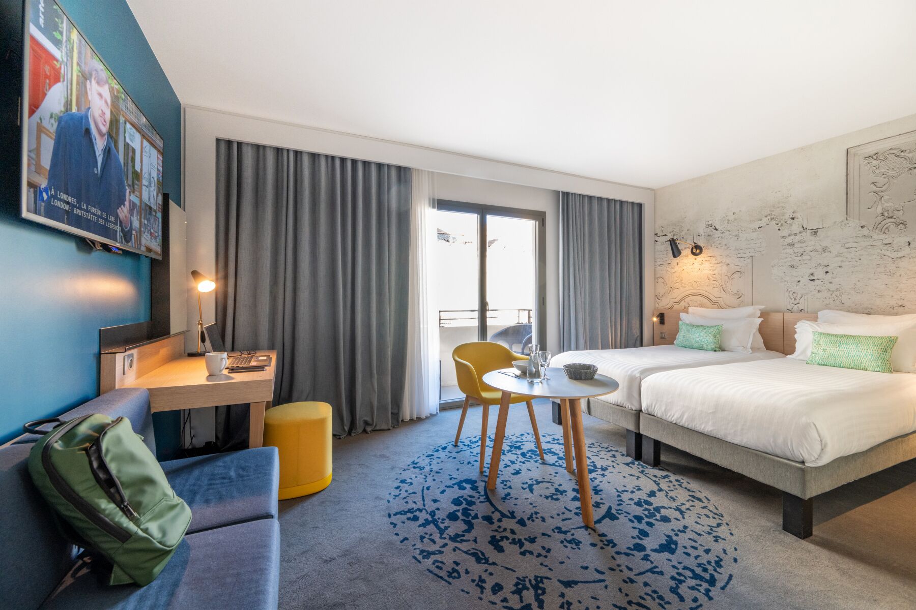 A hotel room with a bed, a desk with a chair, a small table, and a sofa.
