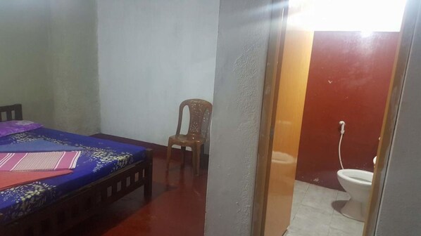 A bedroom with a bed, a chair, and a toilet. - Pure Land Villa (Nallathanniya)