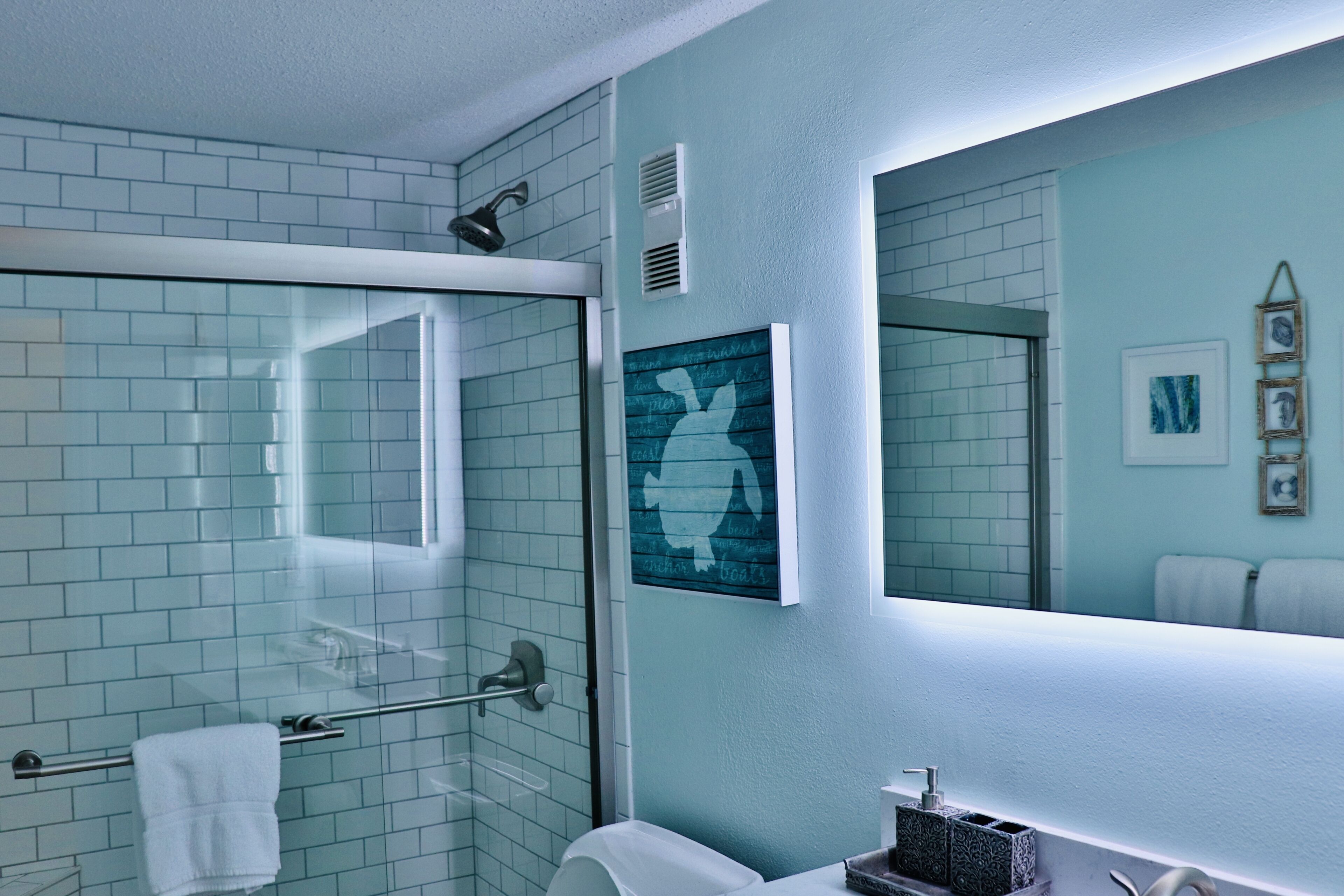 Een badkamer met een douchecabine van glas, een witte wastafel en een spiegel.