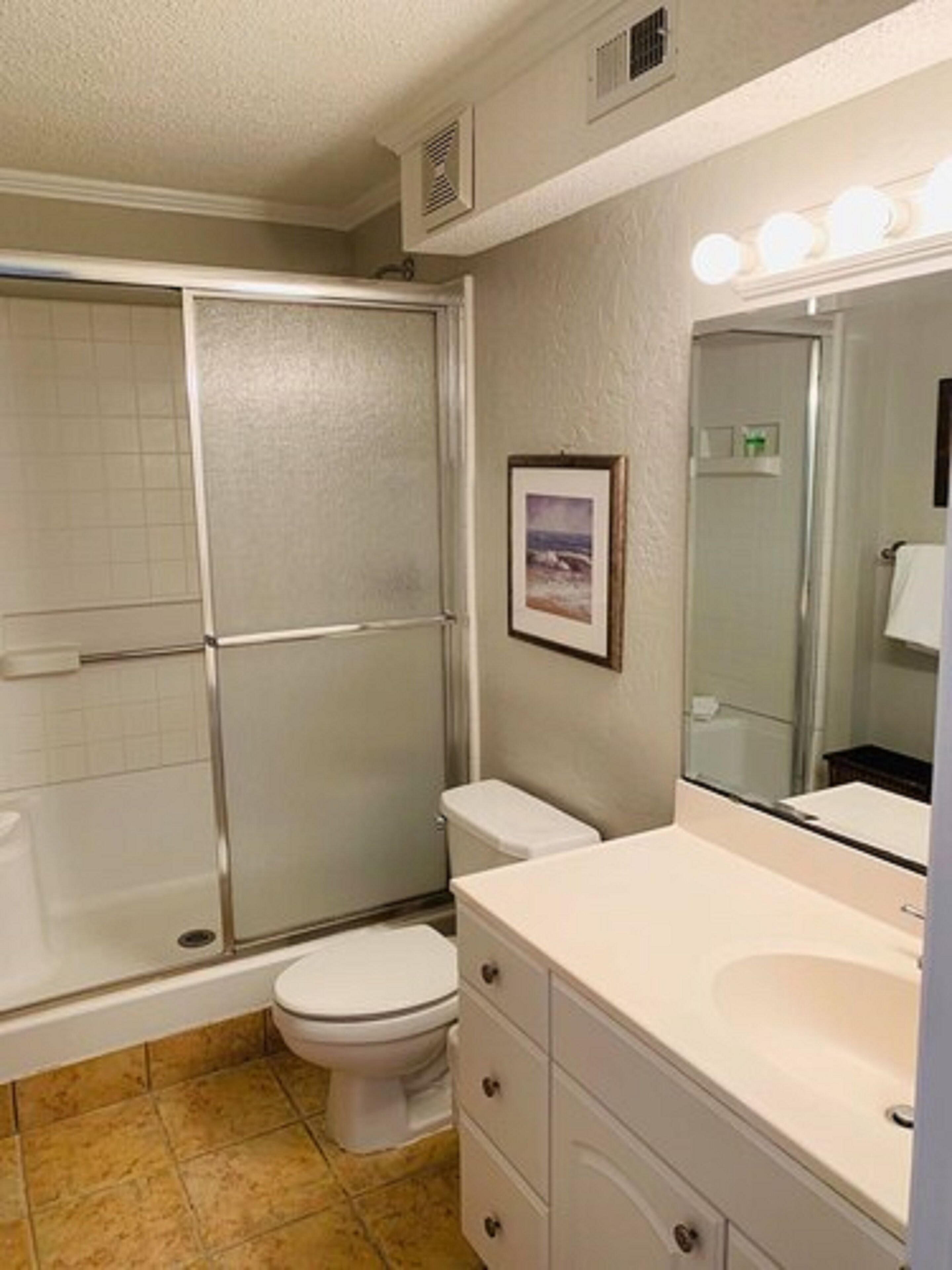 A bathroom with a shower, toilet, and sink.