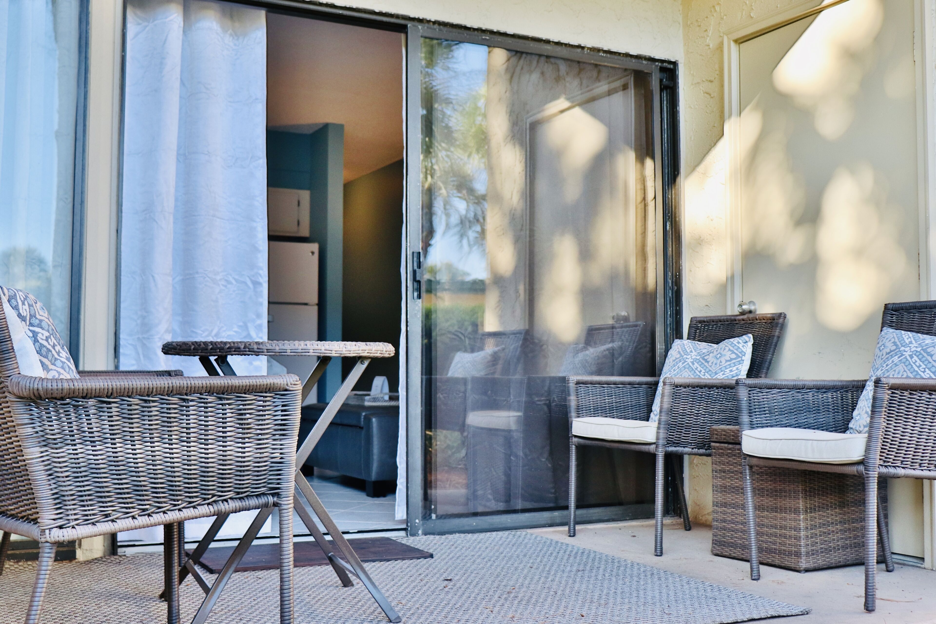 Un espace extérieur aménagé avec des meubles en osier et une porte-fenêtre coulissante donnant sur un patio.