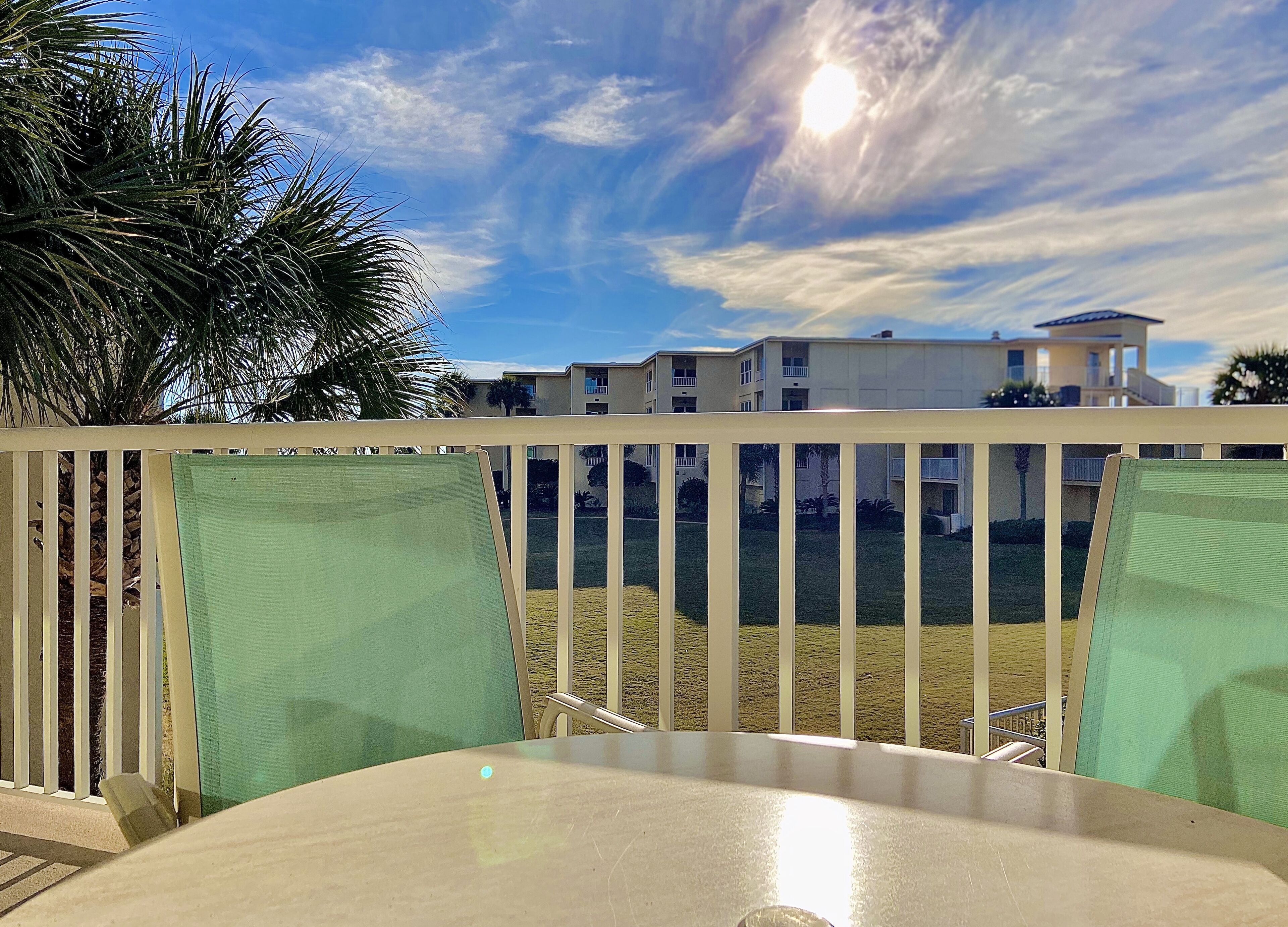 A balcony with a view of a residential area, including a building with multiple balconies and a clear sky.