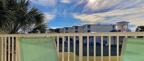 A balcony with a view of a residential area, including a building with multiple balconies and a clear sky.
