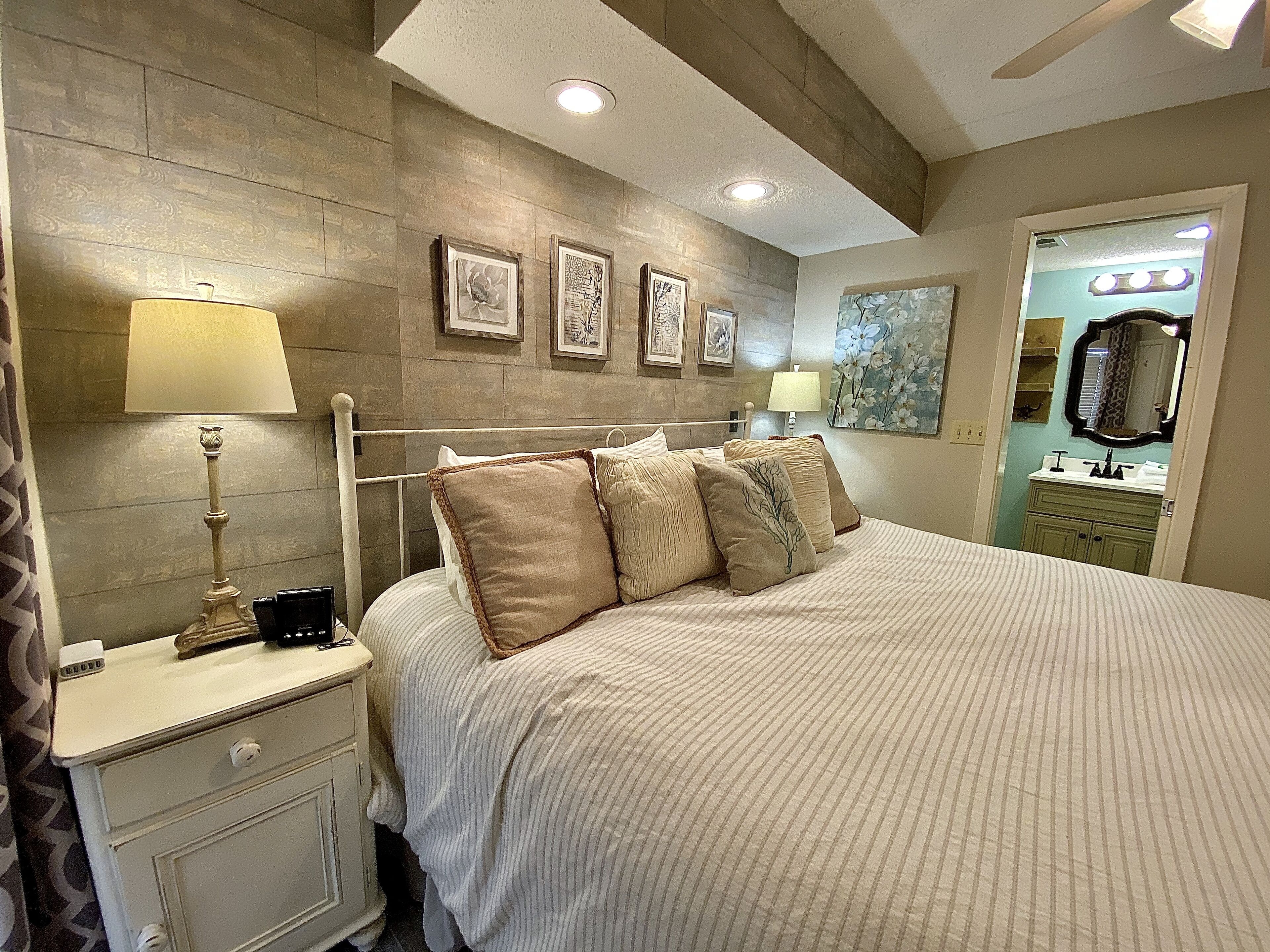 A bedroom with a bed, bedside tables, lamps, and wall art.