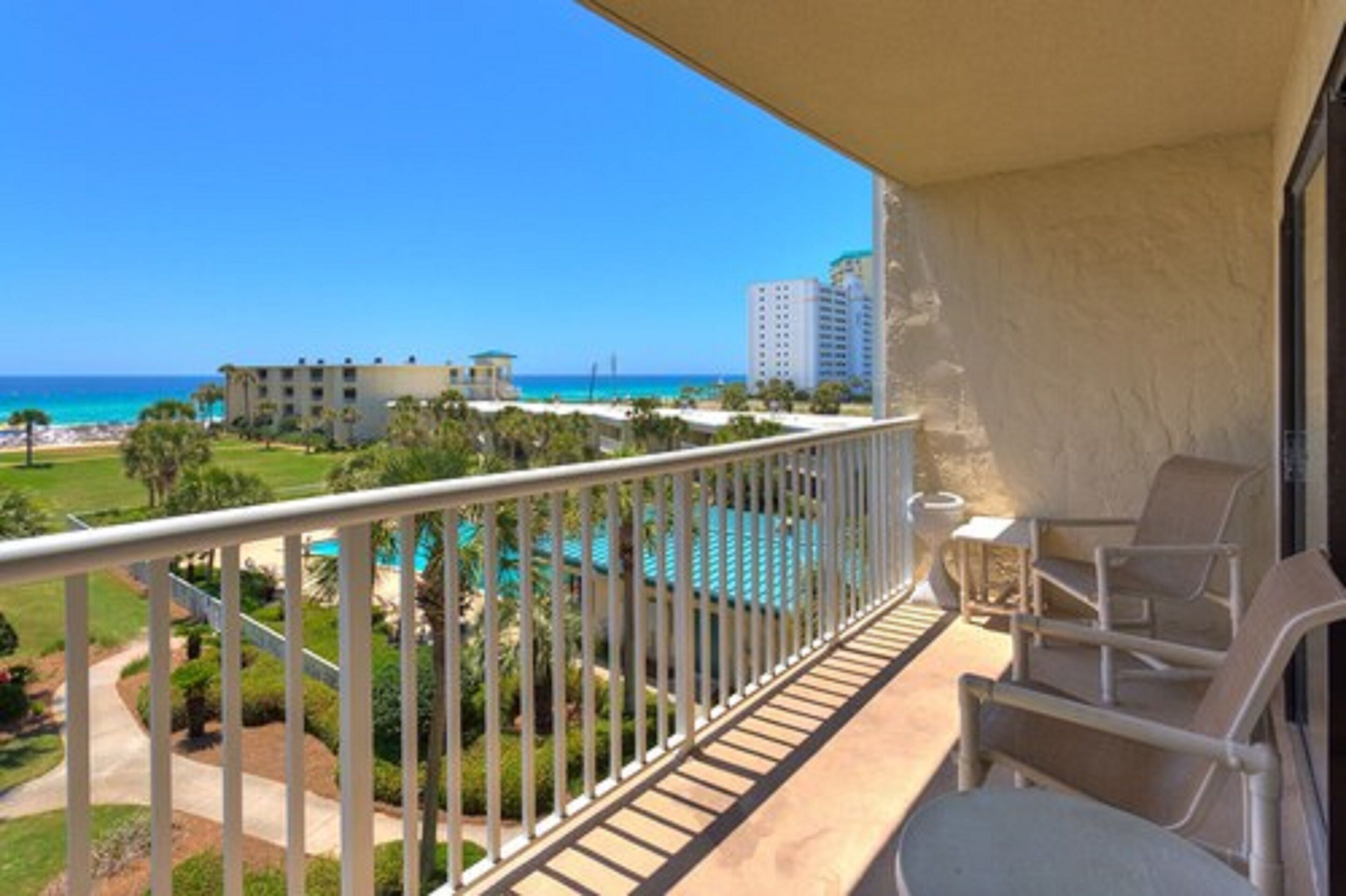 A balcony with a view of the ocean and a pool.