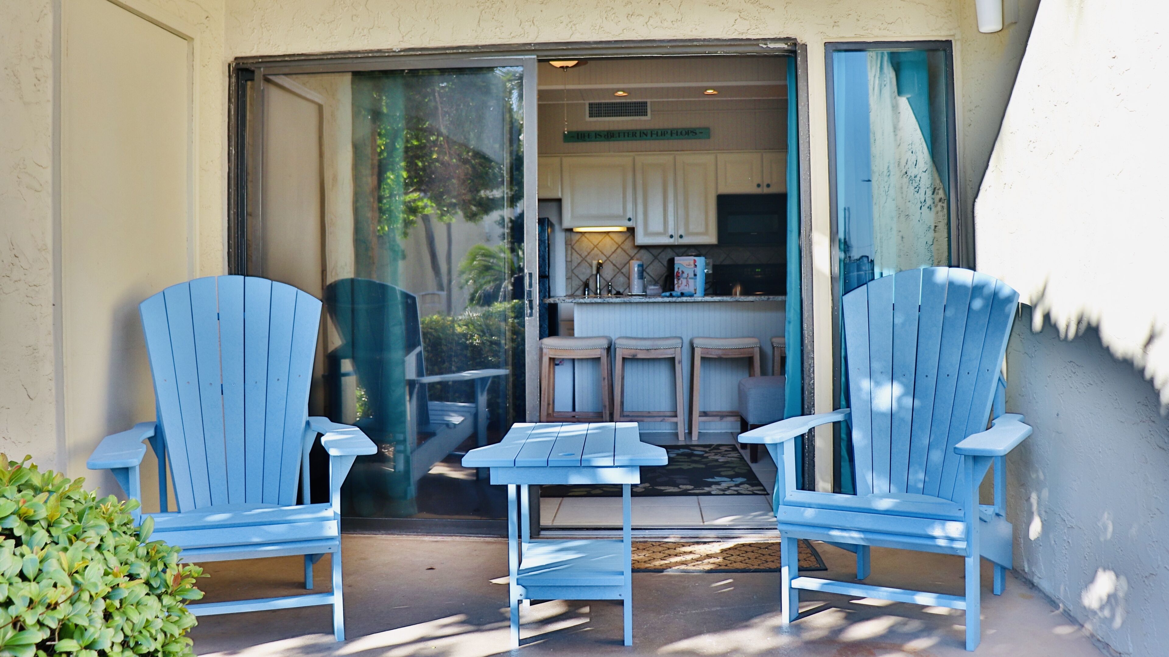 Une terrasse avec deux chaises Adirondack bleues et une petite table.