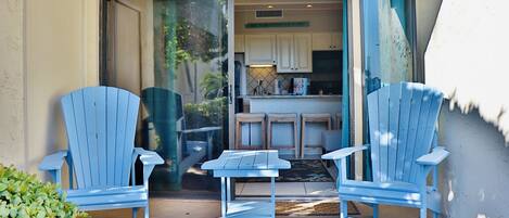 Un patio con dos sillas Adirondack azules y una pequeña mesa.