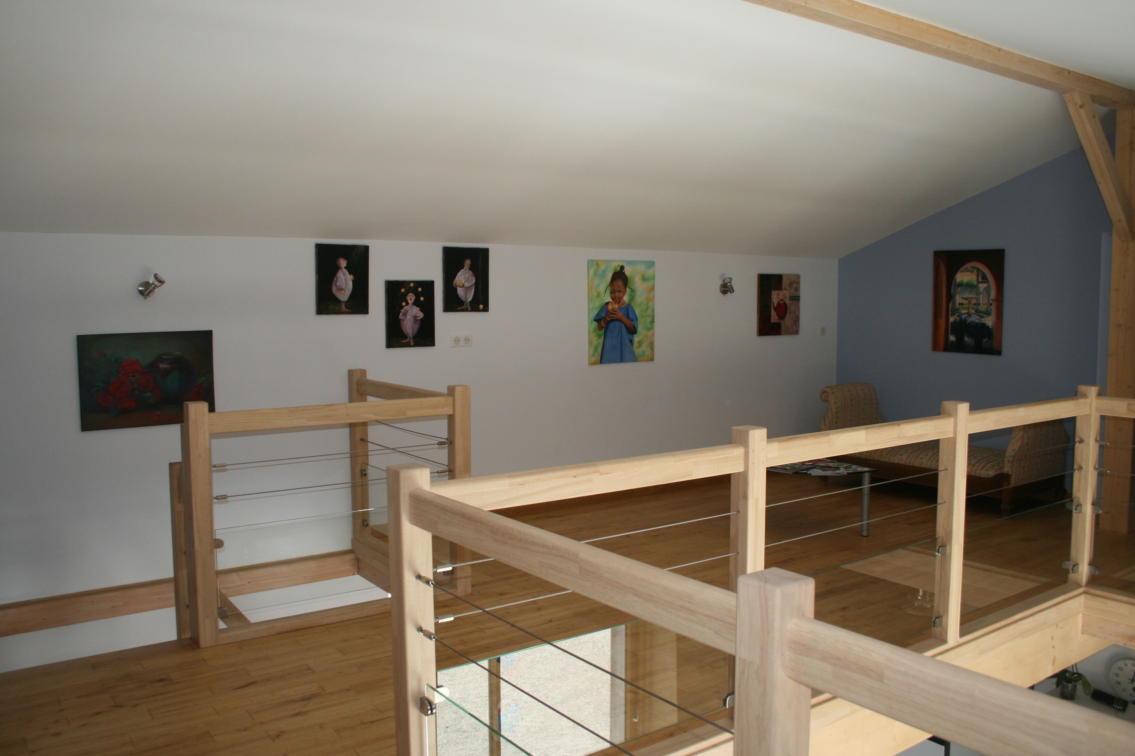 A room with a wooden bunk bed, a small table with a clock, and several framed pictures on the wall.
