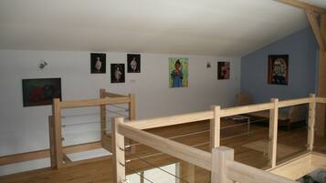 A room with a wooden bunk bed, a small table with a clock, and several framed pictures on the wall.