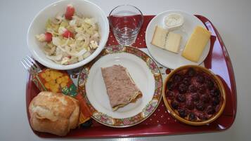 Una bandeja con una variedad de alimentos, incluyendo un tazón de ensalada, un plato de queso, una rebanada de carne, un plato al horno y un panecillo.