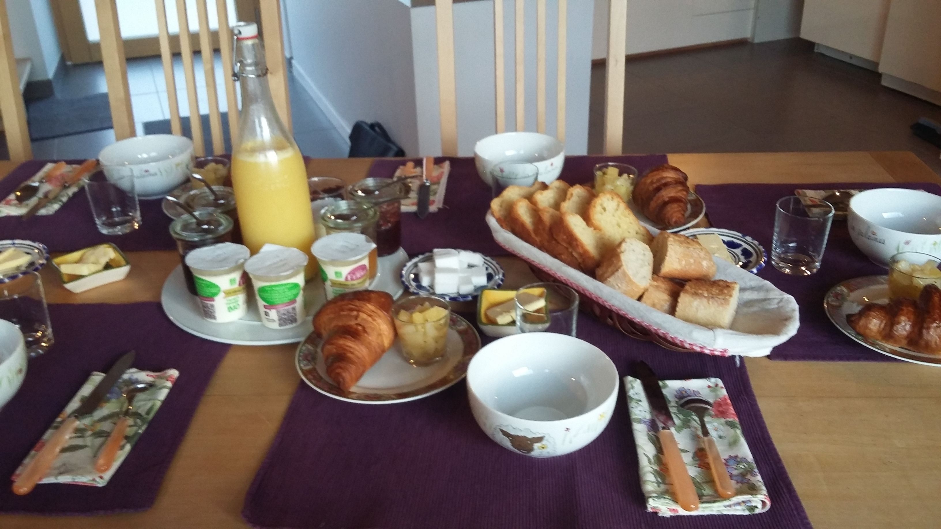 Et morgenbord med croissanter, brød, smør og juice.