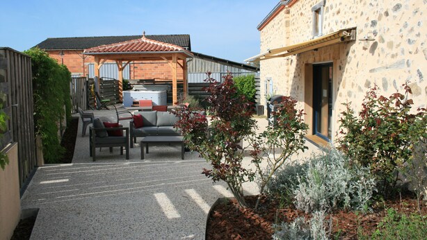 Une cour avec des sièges extérieurs, une pergola et un bâtiment en pierre.