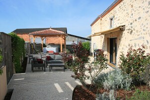A courtyard with outdoor seating, a pergola, and a stone building.