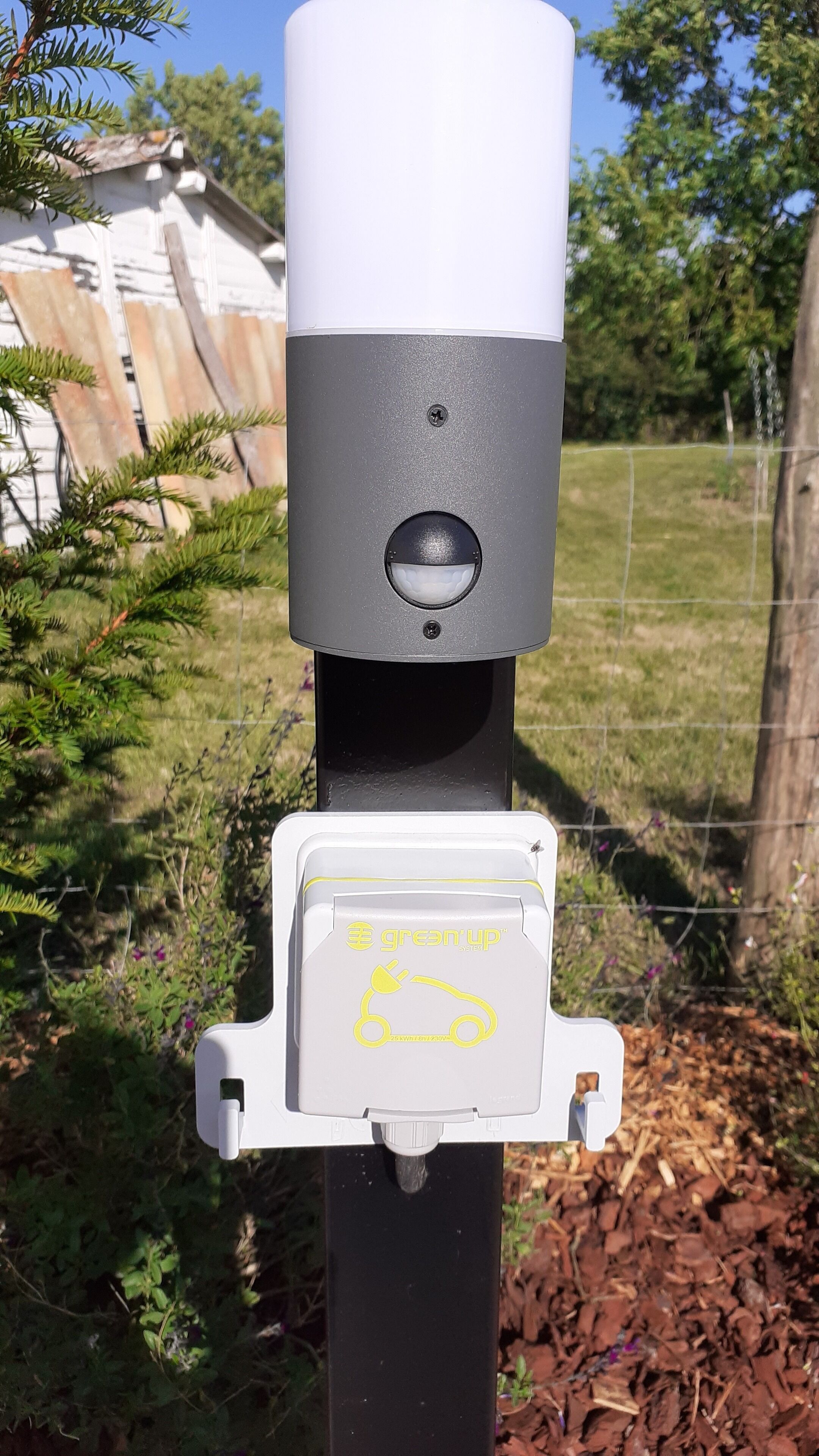 A grey and white outdoor electrical box with a plug and a label that reads "greenup system" and "25kW/230V".