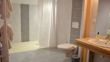 A modern bathroom with a shower, toilet, and sink.
