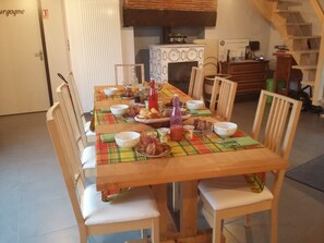 Una mesa de comedor dispuesta con diversos platos y bebidas, rodeada de sillas de madera.